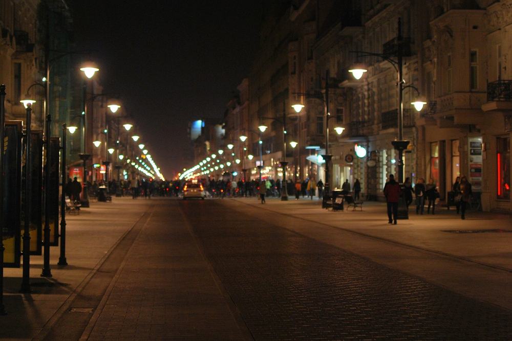 Ulica Piotrkowska w Łodzi nocą, latarnie i oświetlone kamienice